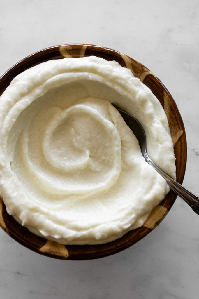 Toum swirled in a traditional Lebanese bowl with a spoon in the toum