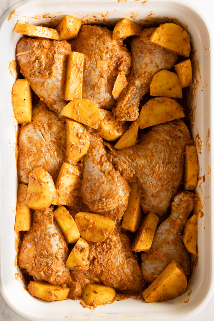 mediterranean marinated chicken and potatoes in a white baking dish