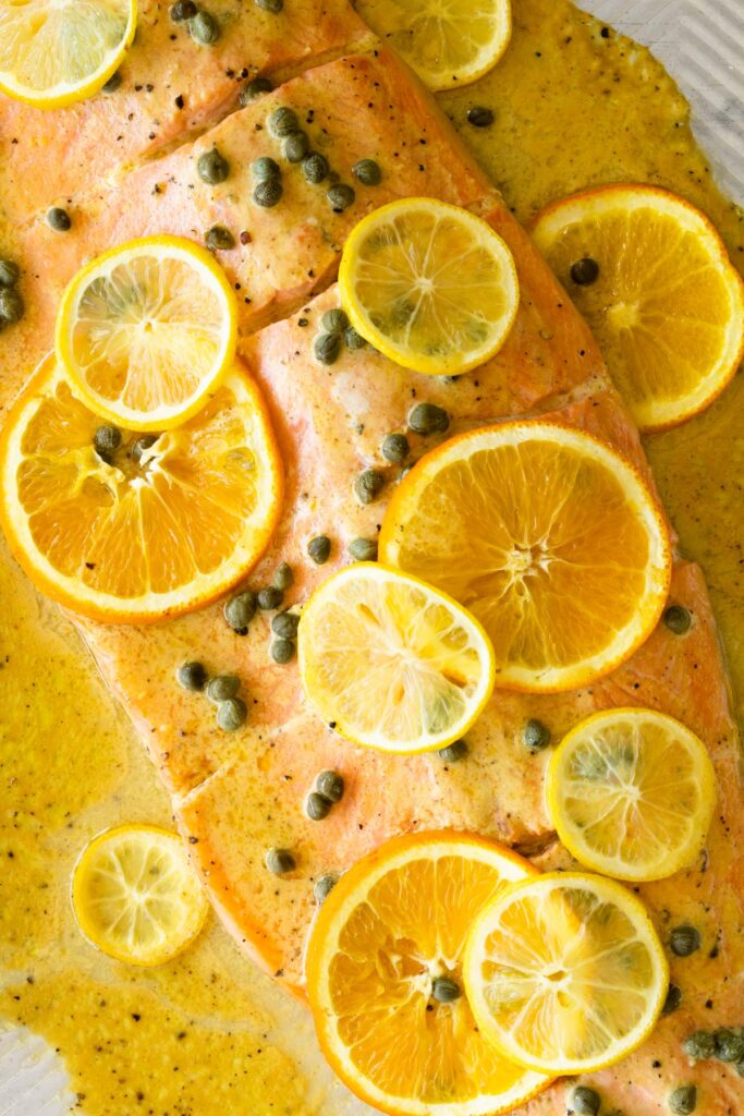slow roasted salmon with citrus and capers on a baking sheet.