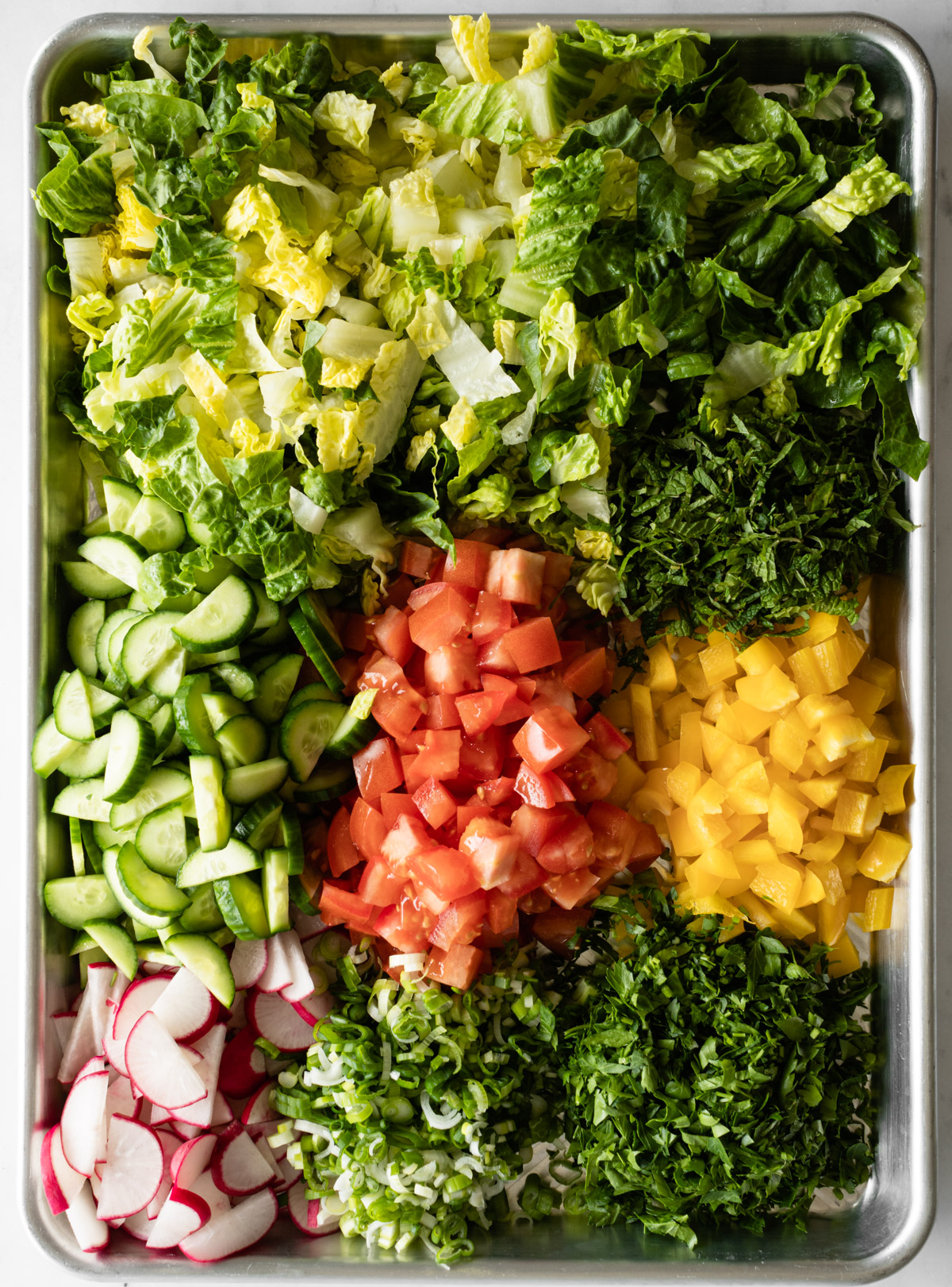 chopped vegetables and herbs in a large tray.