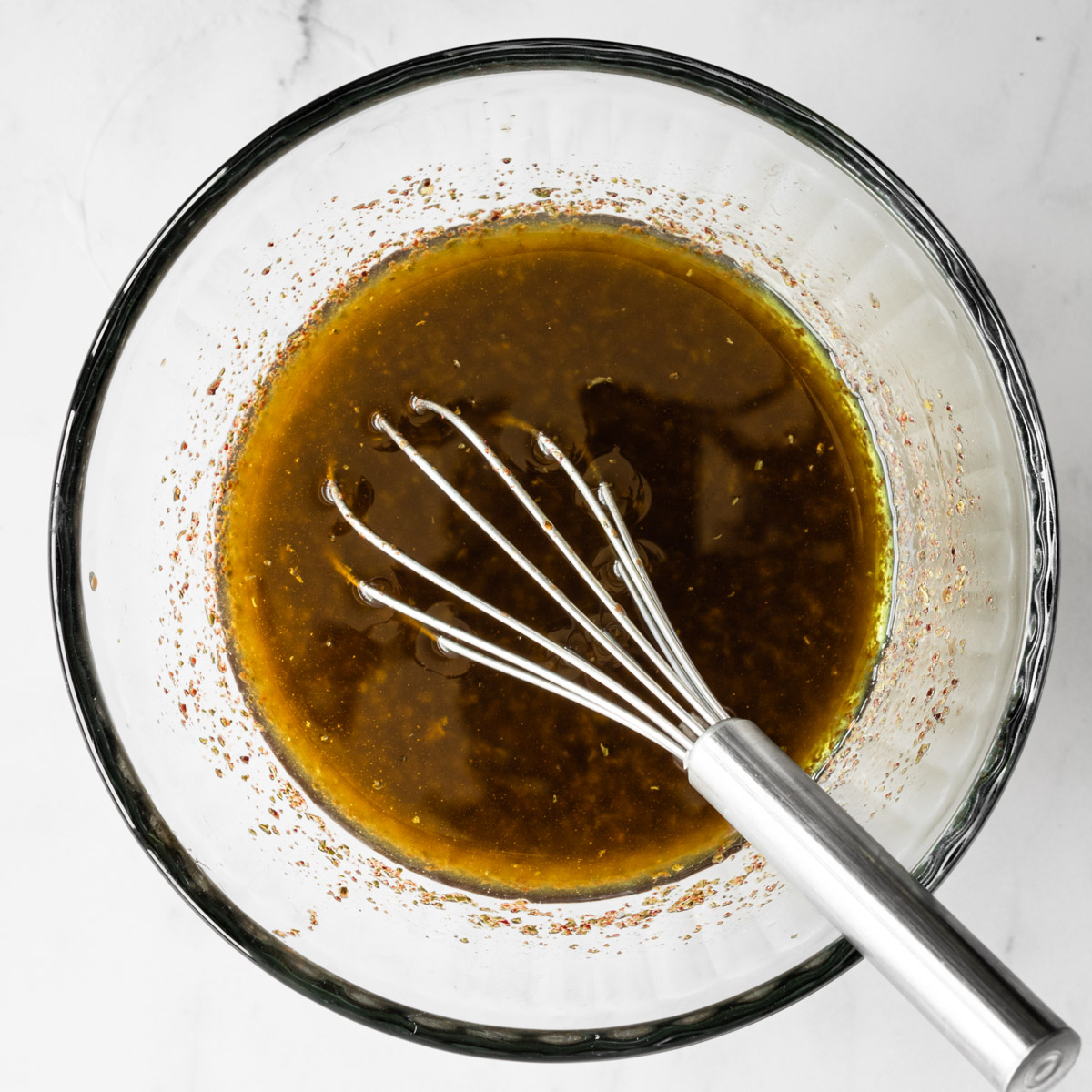 fattoush dressing in a glass bowl with a whisk.