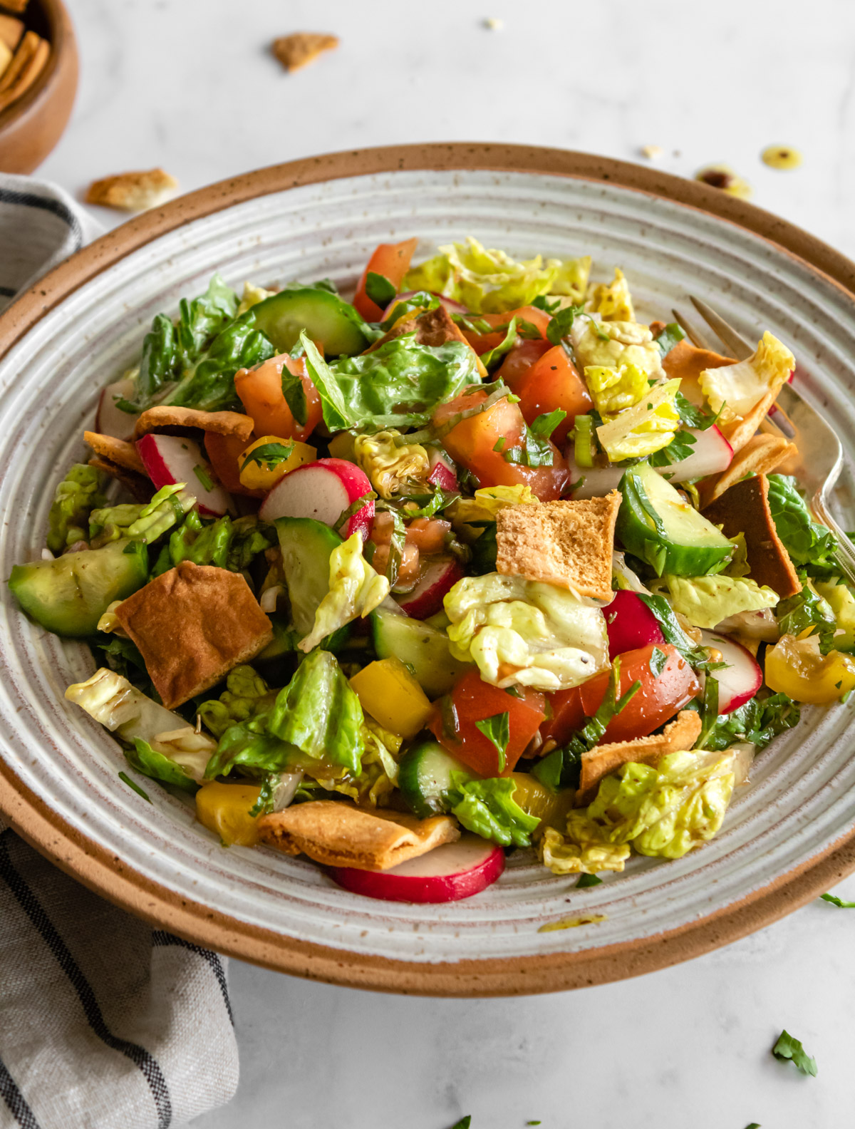 fattoush in a ceramic bowl with a linen napkin on the side.