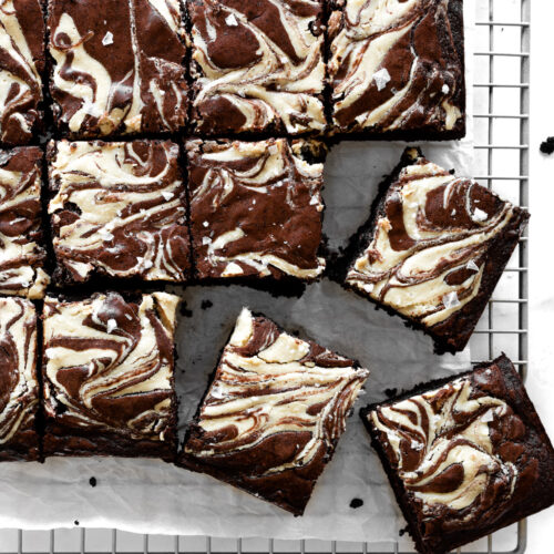 tahini brownies cut into squares on white parchment paper on top of a cooling rack.
