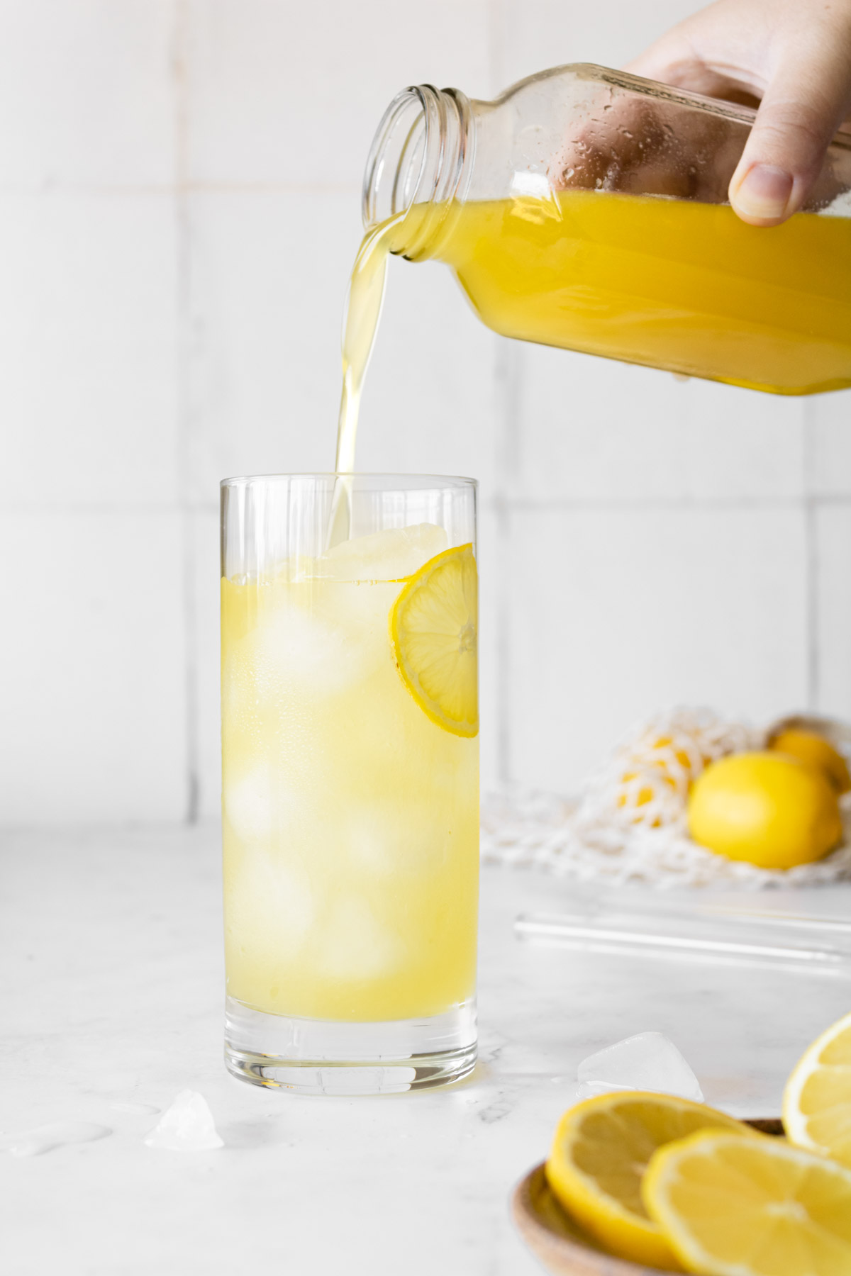 pouring lemon syrup into a glass to make lebanese lemonade.