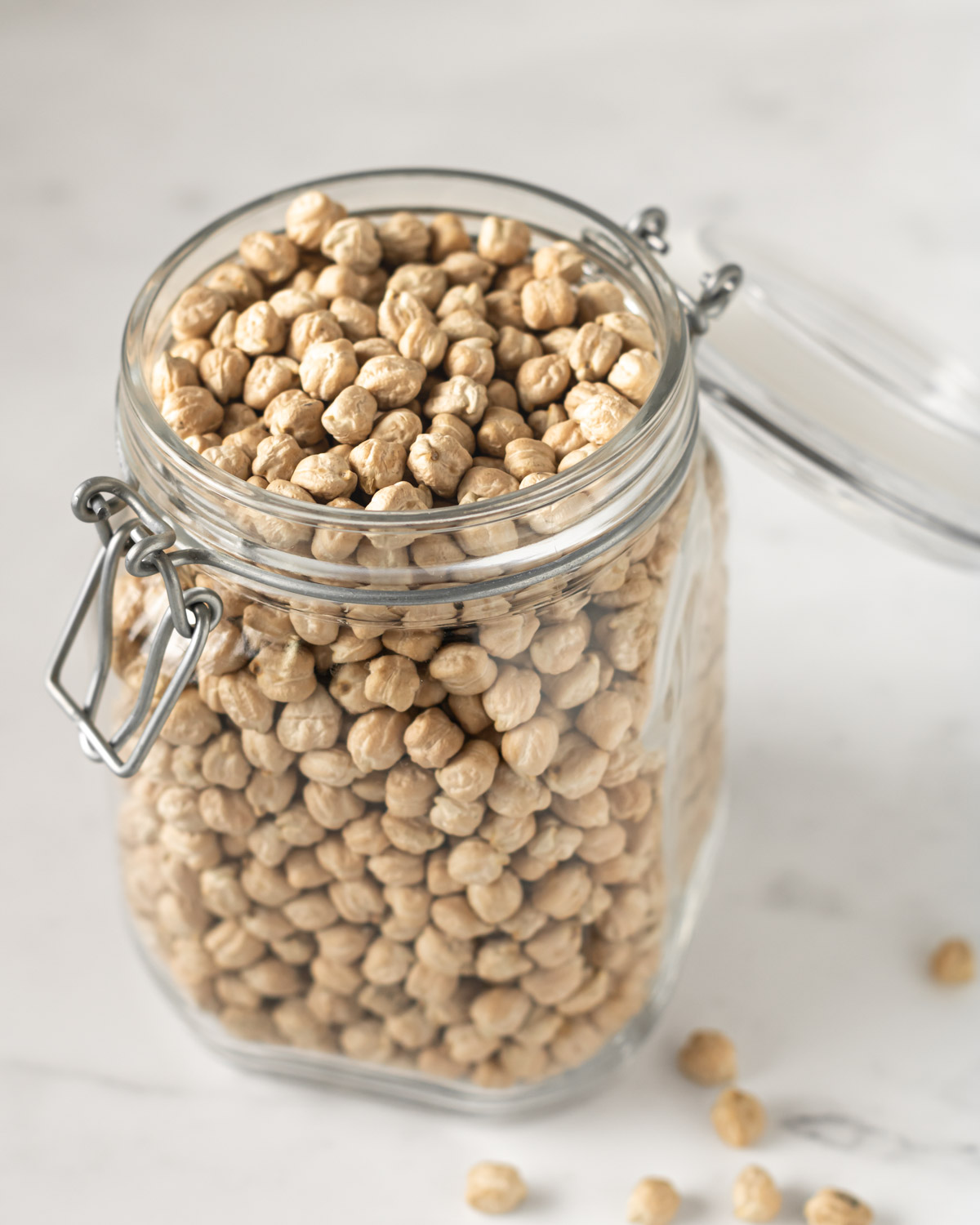 glass jar filled with dried chickpeas on a white counter.