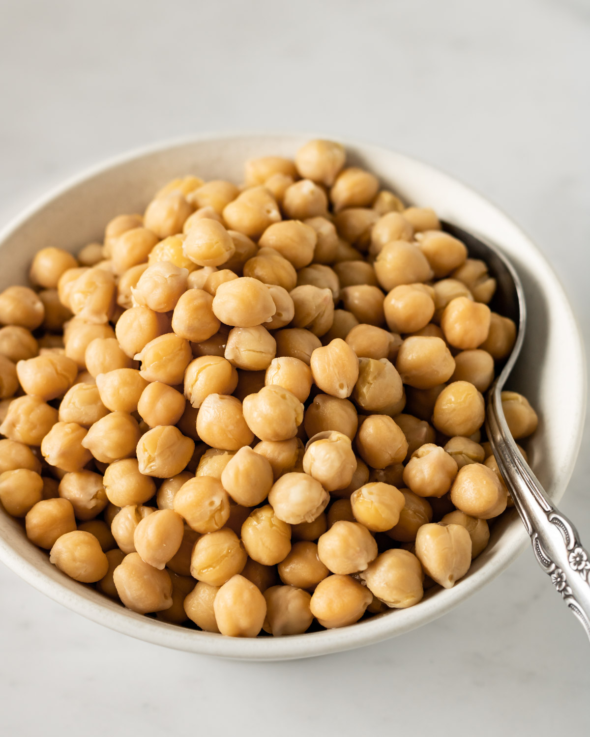 bowl of cooked chickpeas with a spoon in it.