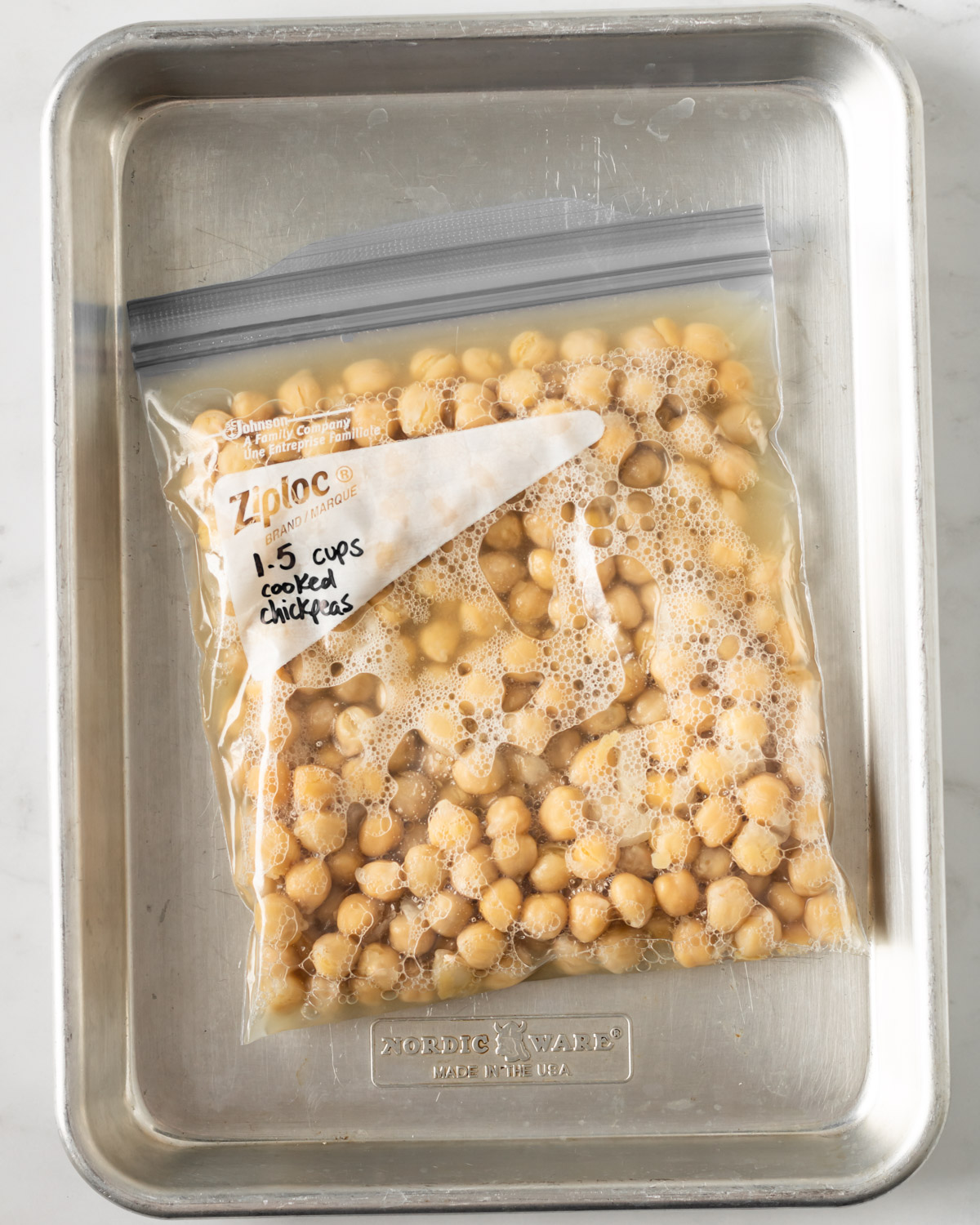 freezer bag filled with chickpeas and aquafaba on a baking sheet.