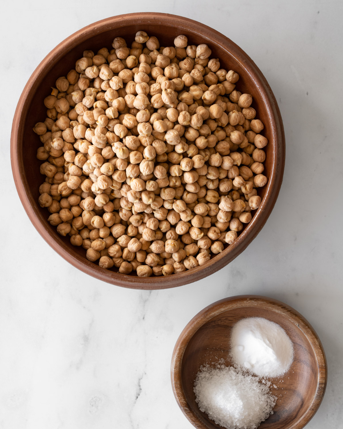 ingredient shot of dried chickpeas with baking soda and salt in bowls.