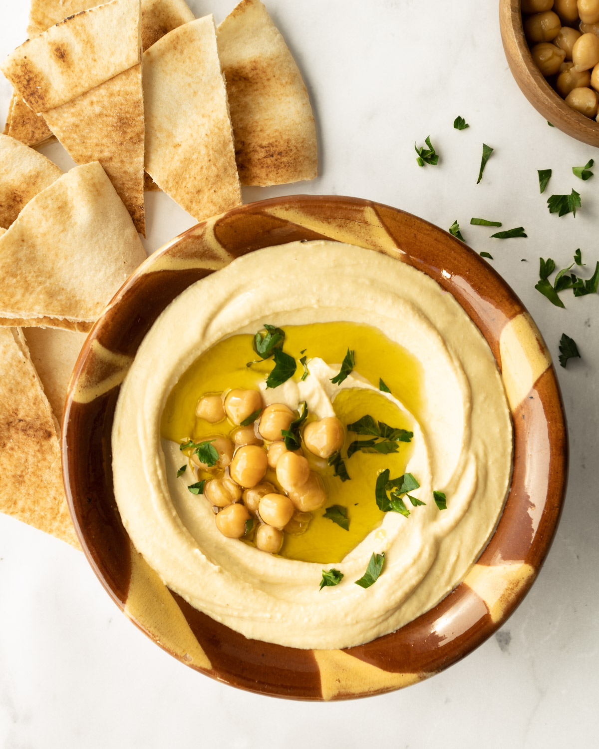 hummus in a traditional Lebanese clay bowl with garnishes.