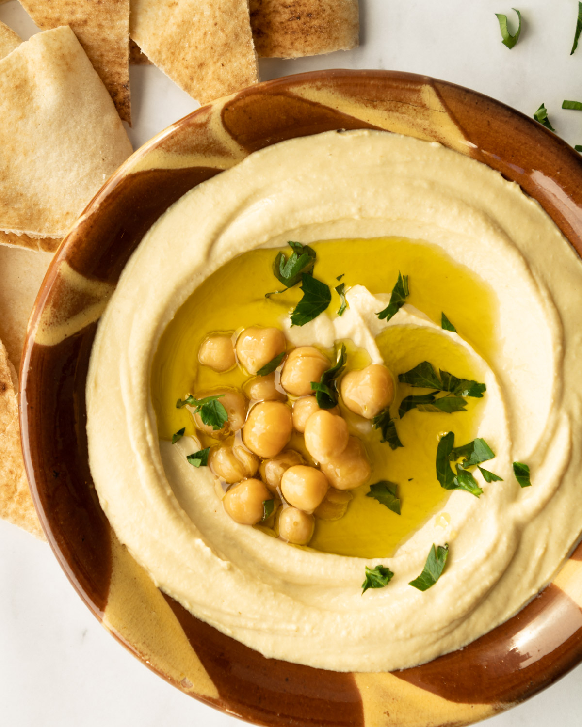 hummus in a traditional Lebanese clay bowl with garnishes.