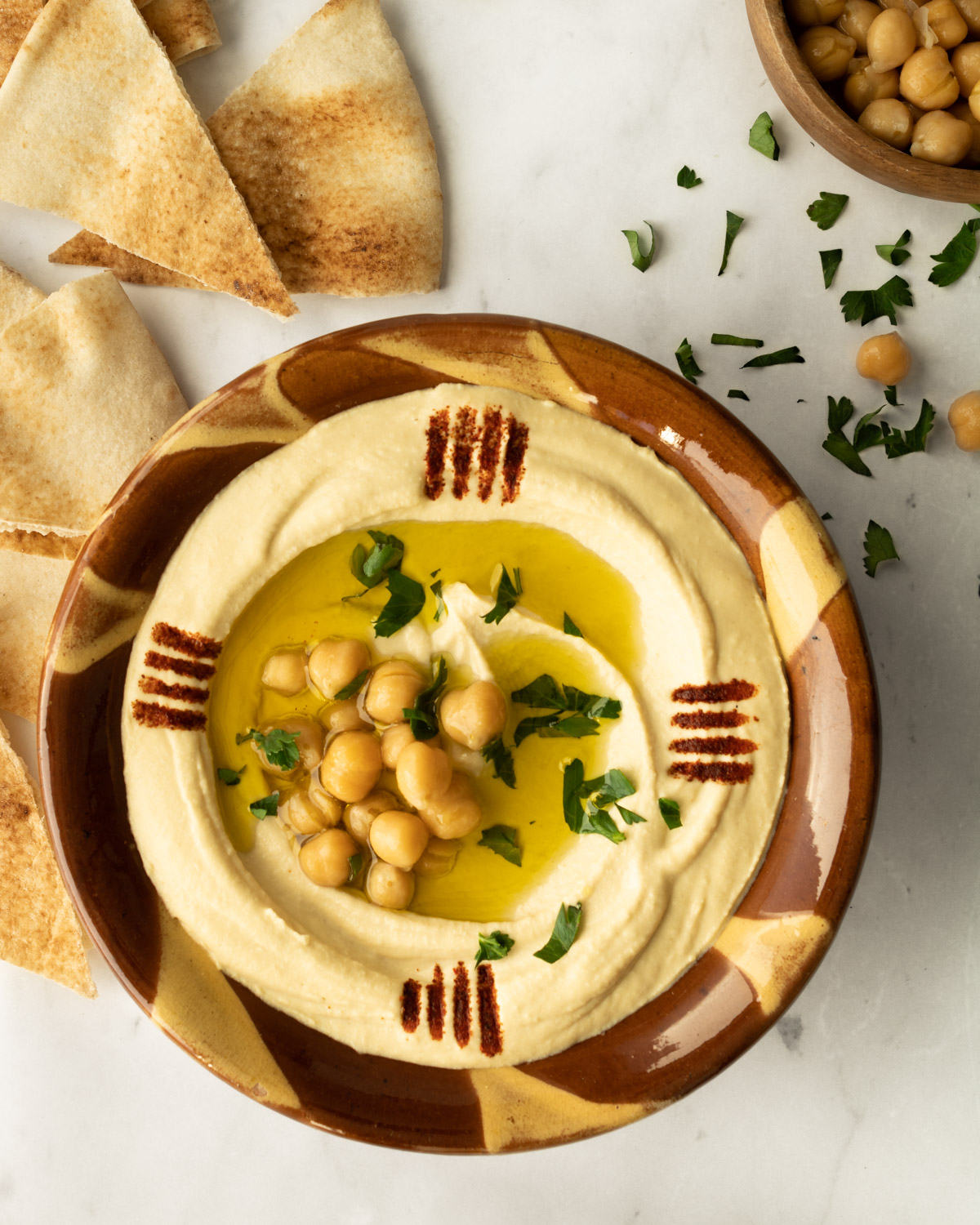 hummus in a traditional Lebanese clay bowl with garnishes.