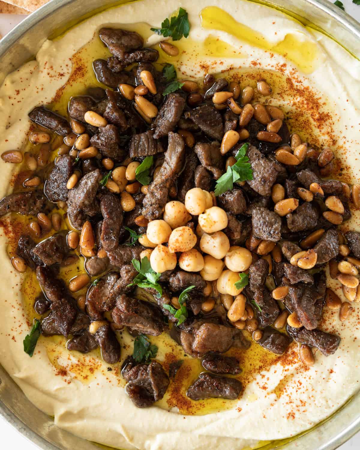 close up of spiced meat and pine nuts on top of hummus.