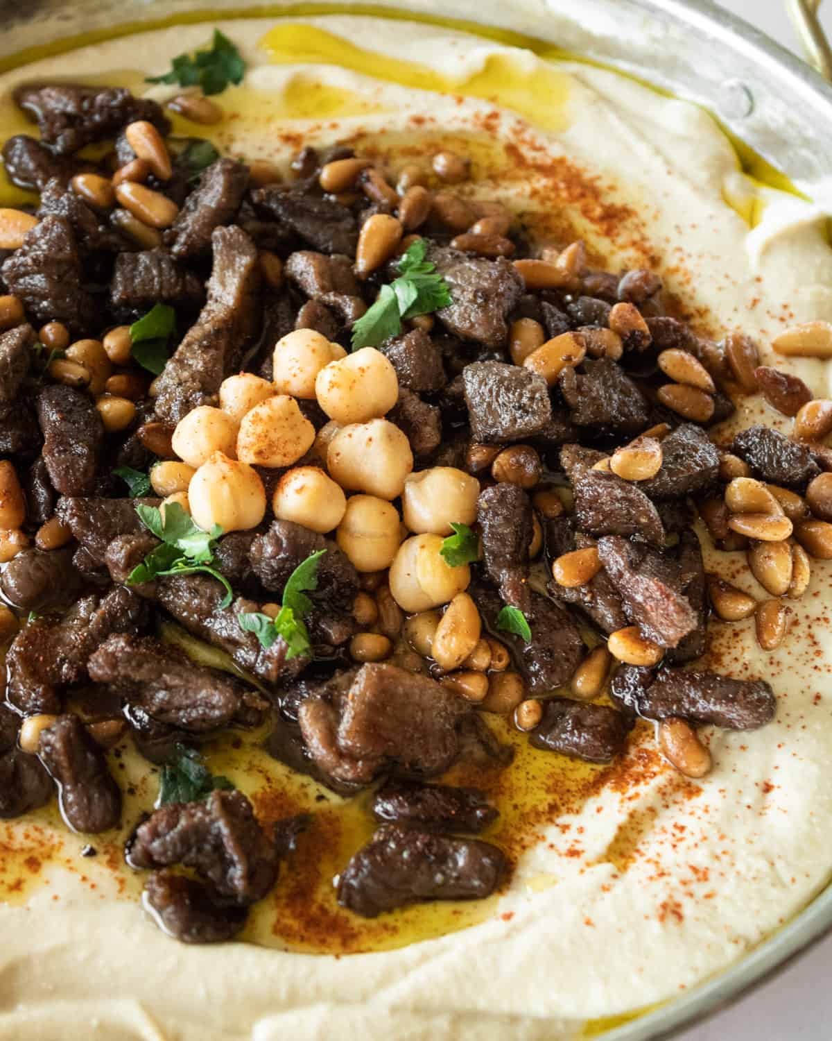 close up of spiced meat and pine nuts on top of hummus.