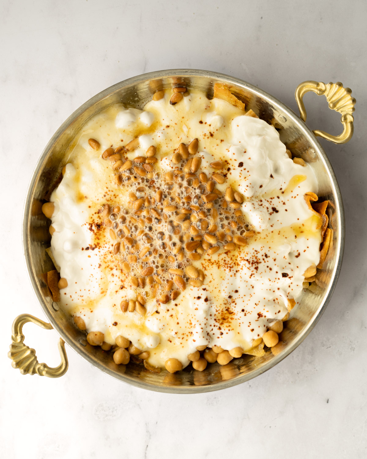 pine nuts in ghee sizzling on top of the bowl of chickpea fatteh.