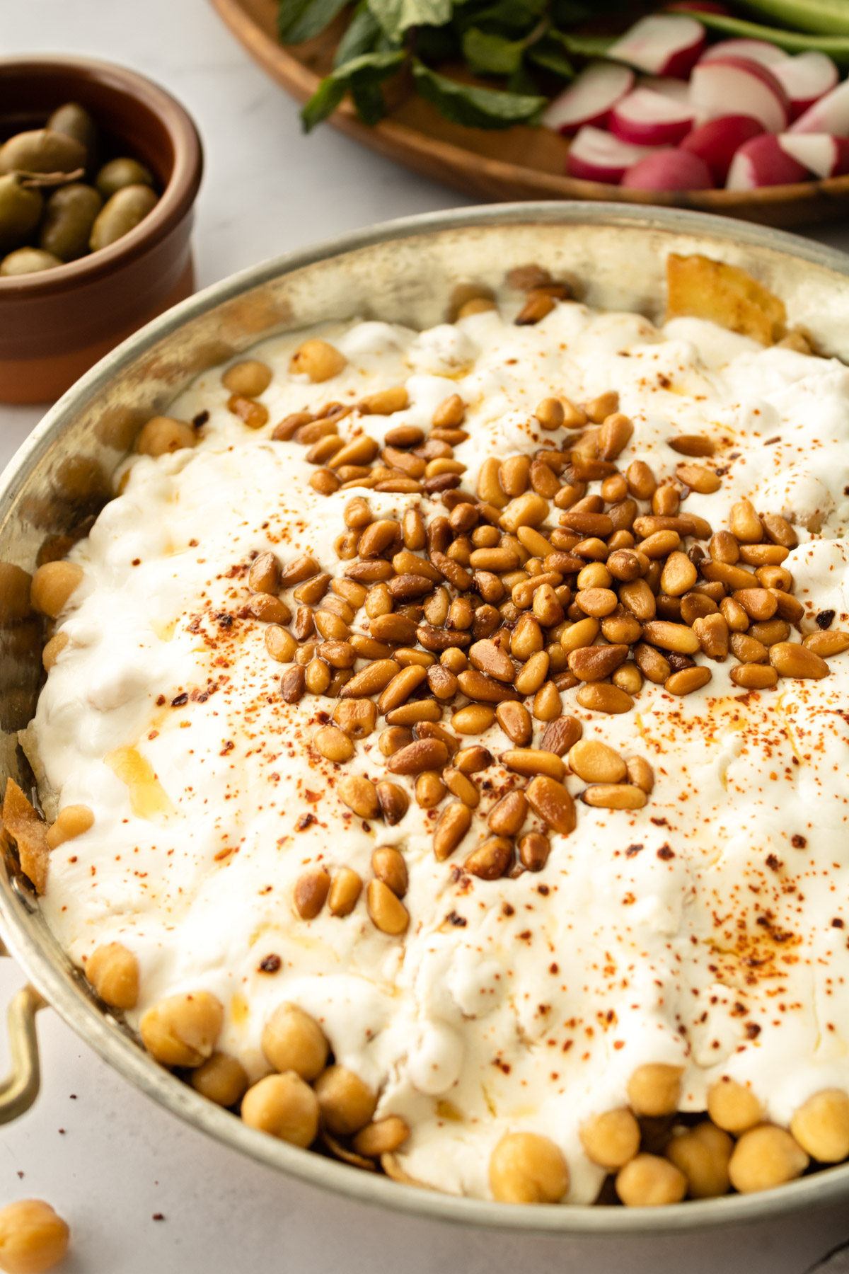 close up of fattet hummus with olives on the side.
