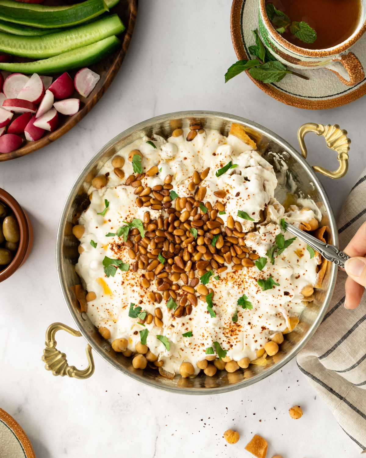 hand scooping up chickpea fatteh with a spoon.