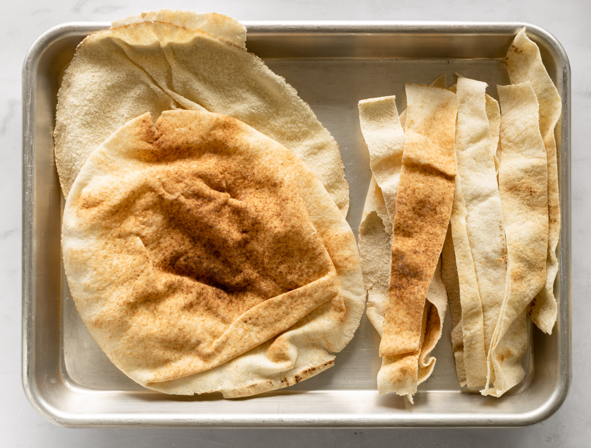 pita bread separated in half and cut into strips on a baking sheet.