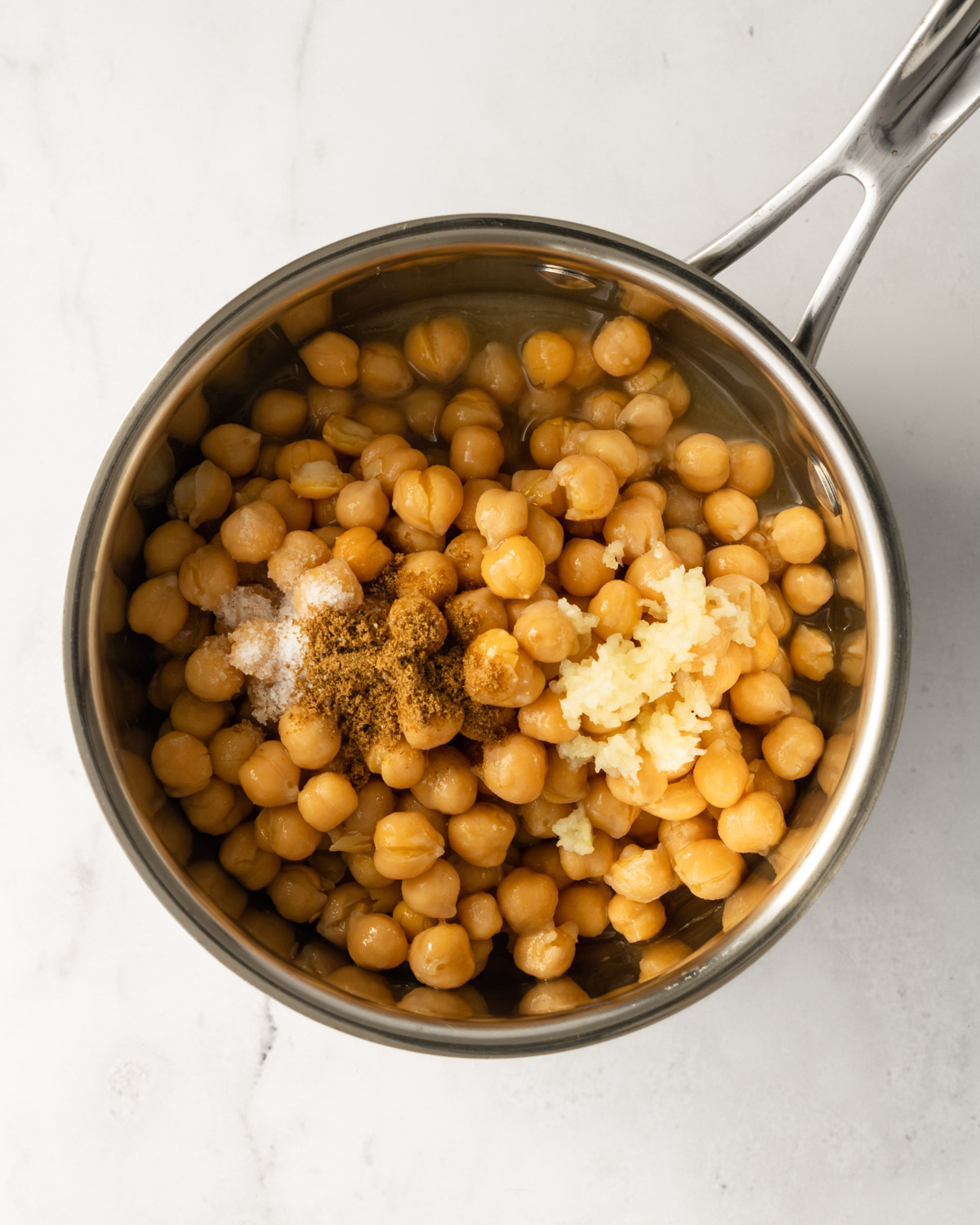 a small saucepan with cooked chickpeas, garlic, salt, and cumin.